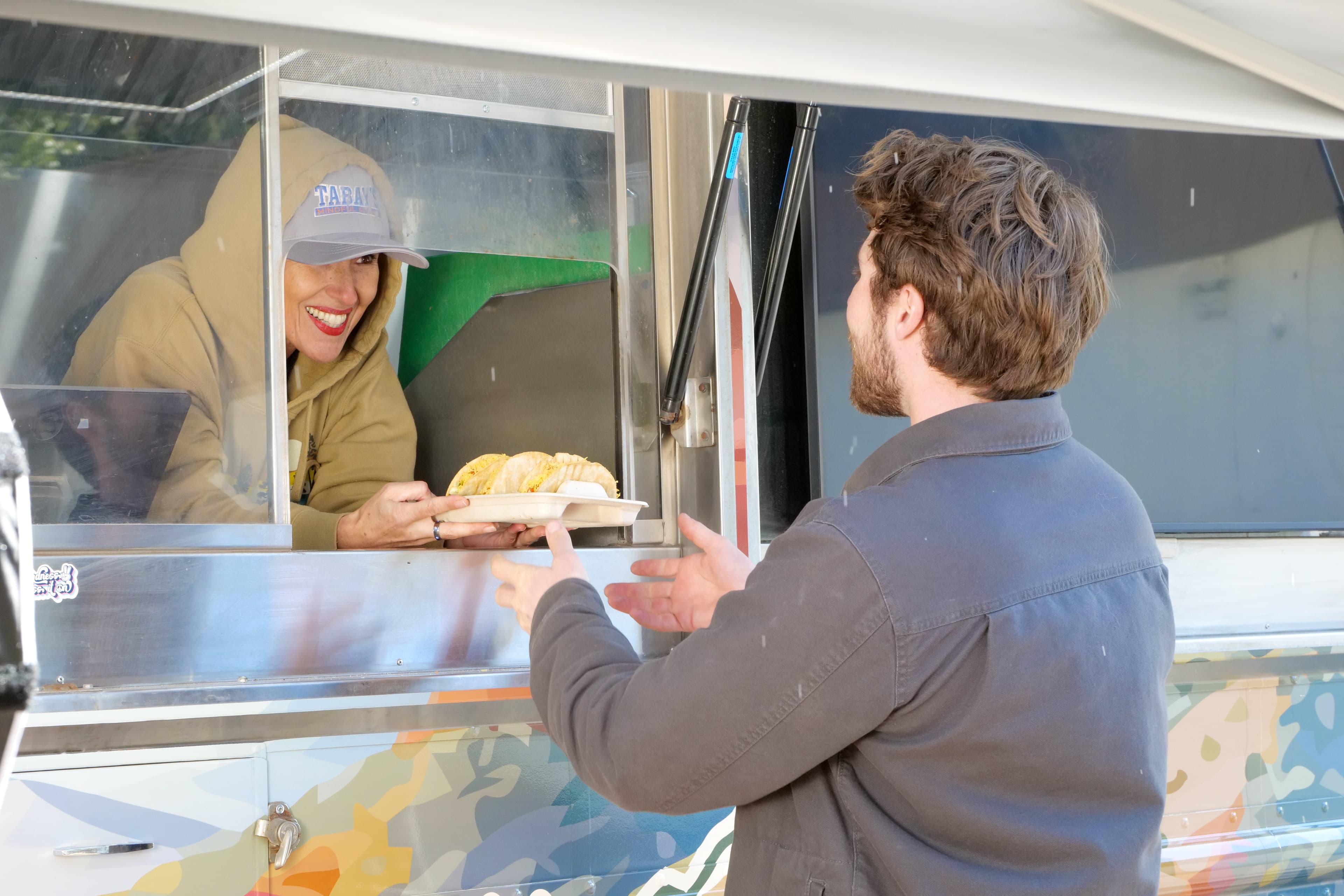 Sahel serving food through the Tabay's Mindful Kitchen truck window
